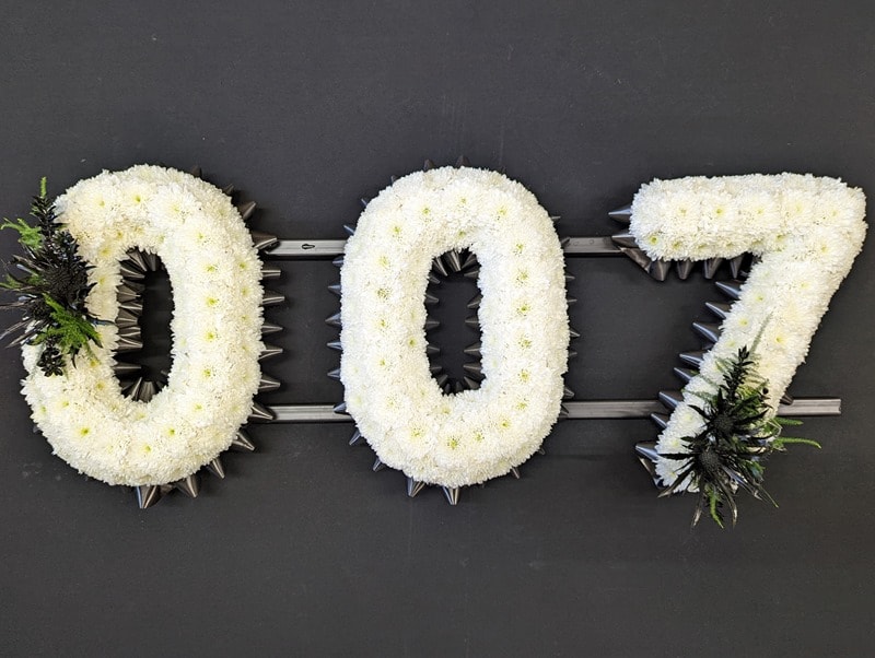 007 number funeral tribute in white chrysanthemums with dark ribbon and black foliage