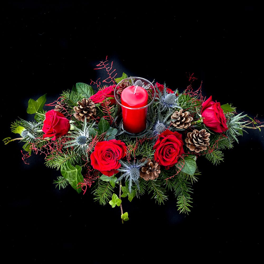 Red roses, pinecones, and candle Christmas arrangement