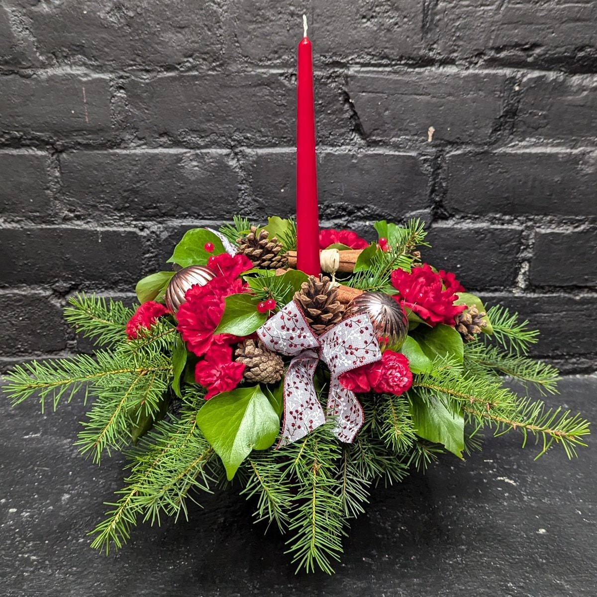 Christmas flower candle with red blooms and greenery