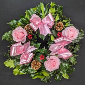 Holly graveside Christmas wreath with pink bows, blush rose accents, pinecones and red berries