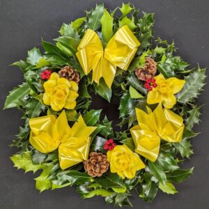 Holly graveside Christmas wreath with yellow bows, yellow rose accents, pinecones and red berries