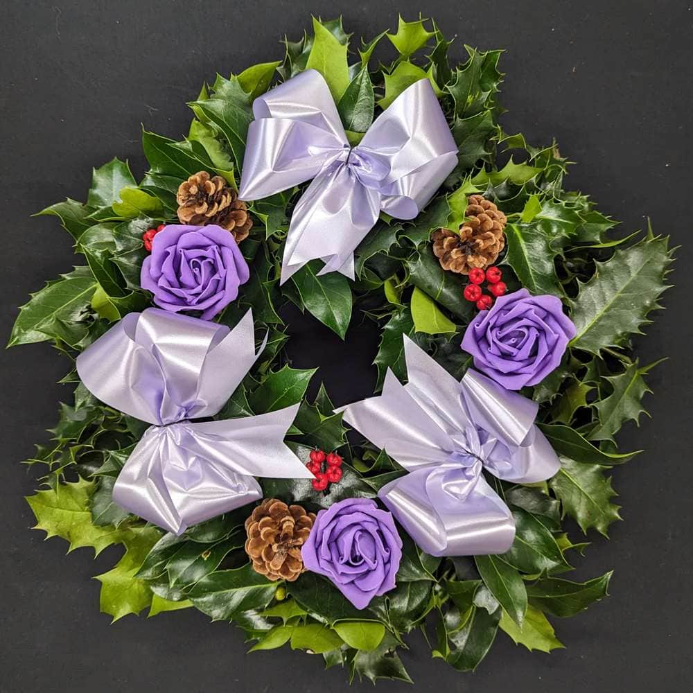 Holly graveside Christmas wreath with lilac bows, purple rose accents, pinecones and red berries