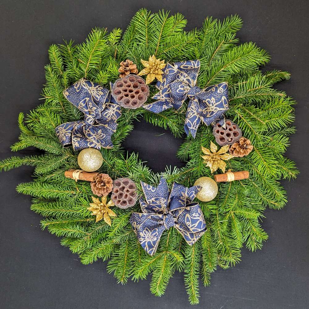 Navy and gold pine Christmas door wreath with bows, gold baubles, pinecones, lotus pods and cinnamon