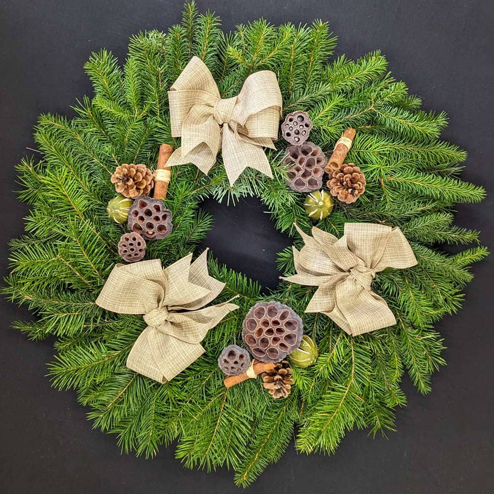 Pine Christmas door wreath with neutral linen-style bows, pinecones, lotus pods and cinnamon