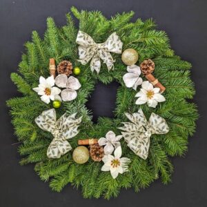 White and silver pine Christmas door wreath with white bows, poinsettia, pinecones and gold baubles
