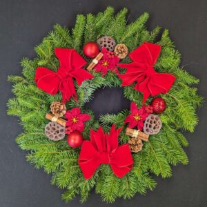 Pine Christmas door wreath with red bows, red baubles, poinsettia, pinecones and cinnamon
