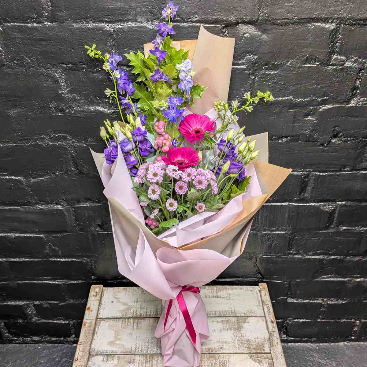 Bright pink and purple hand-tied bouquet with gerberas, lisianthus and seasonal flowers in lilac and kraft wrap, tied with a pink ribbon – Anastasia Florists Aberdeen - Close up