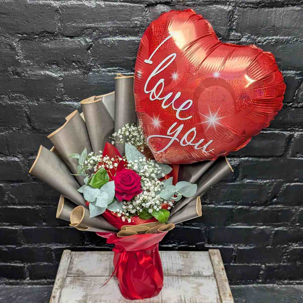 Single red rose arrangement with white Gypsophila, eucalyptus, and a large heart-shaped 'I Love You' balloon