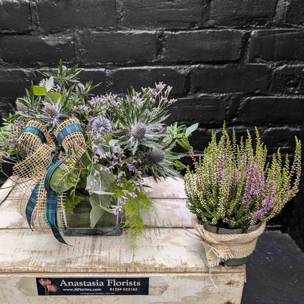 Scottish thistle and heather flower arrangement with lilac blooms, foliage and tartan ribbon in a glass cube vase – Anastasia Florists Aberdeen - Split View