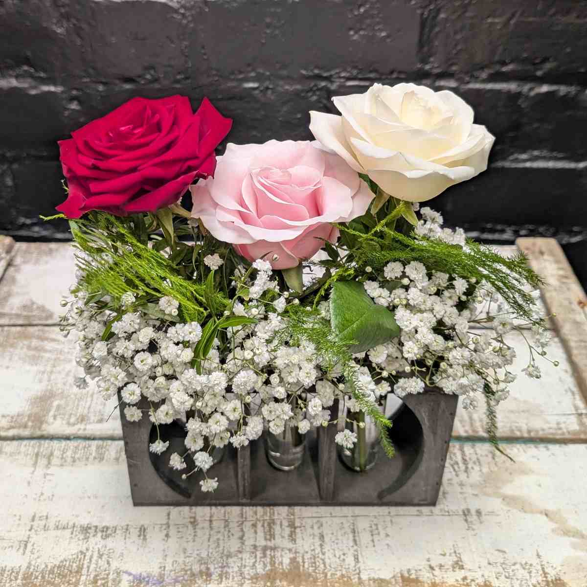 Trio of red, pink, and white roses in a simple arrangement – close-up