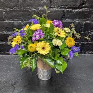 Colourful arrangement of seasonal flowers in a tin – angle view