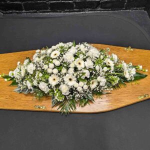 All white coffin spray with gerberas, carnations and gypsophila on wooden coffin