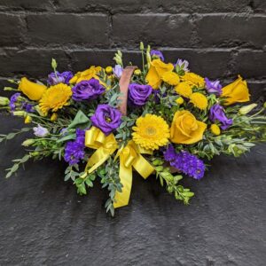 Vibrant arrangement of fresh seasonal flowers in a rustic woven basket, perfect for a cheerful gift or sympathy.