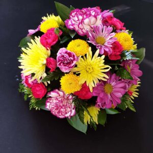Bright mixed funeral posy with yellow chrysanthemums, pink carnations and lilac flowers