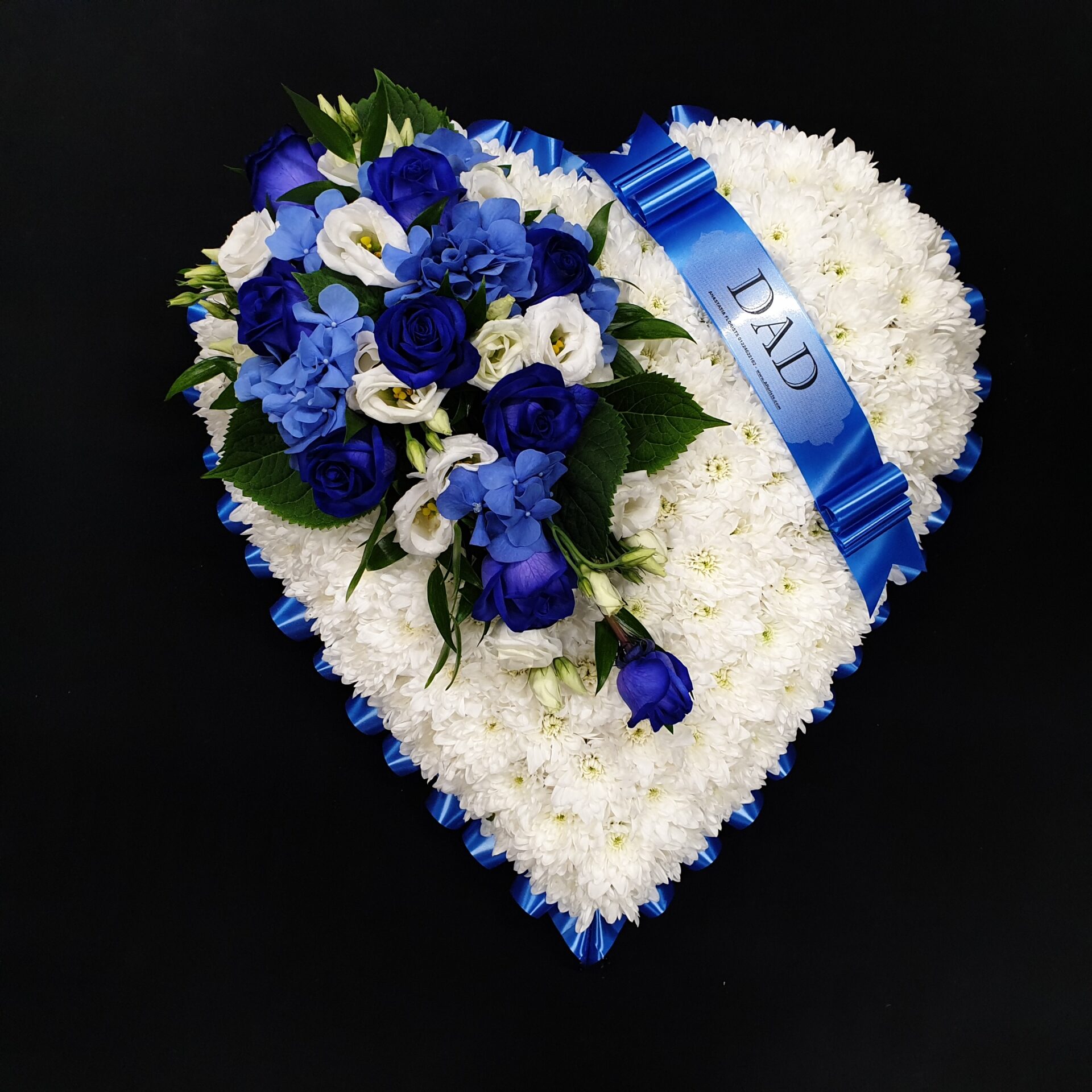 White chrysanthemum heart funeral tribute with blue and white flowers and blue Dad ribbon on a black background