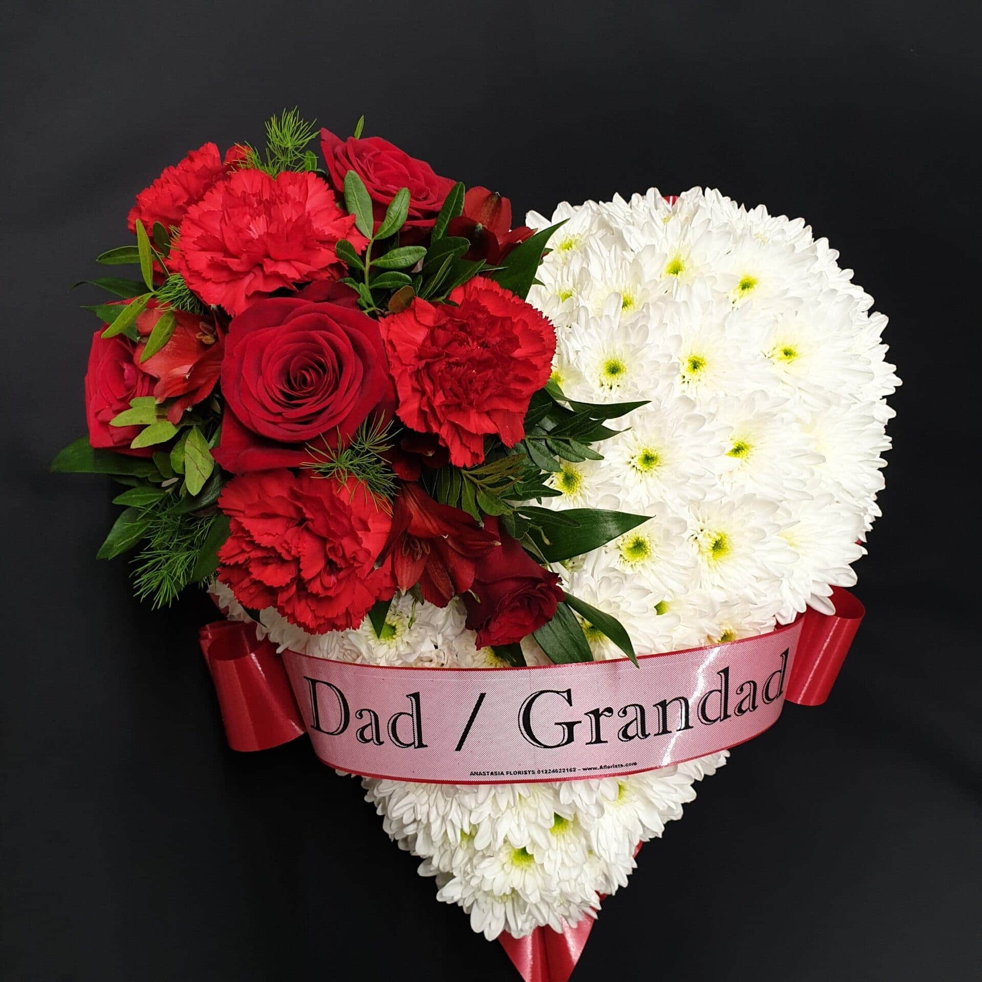 White chrysanthemum heart funeral tribute with red roses, carnations and Dad / Grandad ribbon on a black background