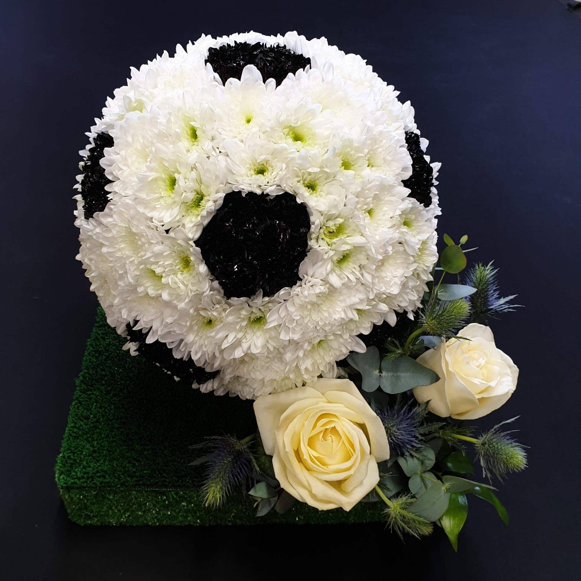 Floral football tribute with white roses and greenery