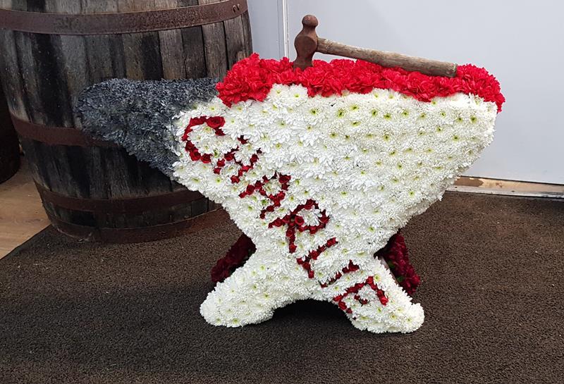 Floral tribute shaped as an anvil and hammer for funerals