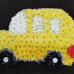 Yellow and white floral funeral car tribute arrangement.