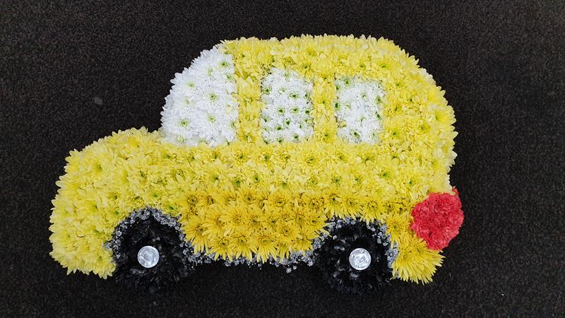 Yellow and white floral funeral car tribute arrangement.