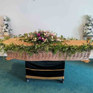 Natural coffin garland on wicker coffin with pink and cream flowers