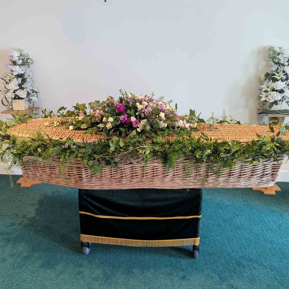 Natural coffin garland on wicker coffin with pink and cream flowers