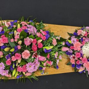 Pink and purple coffin spray with matching 14-inch wreath on wooden coffin