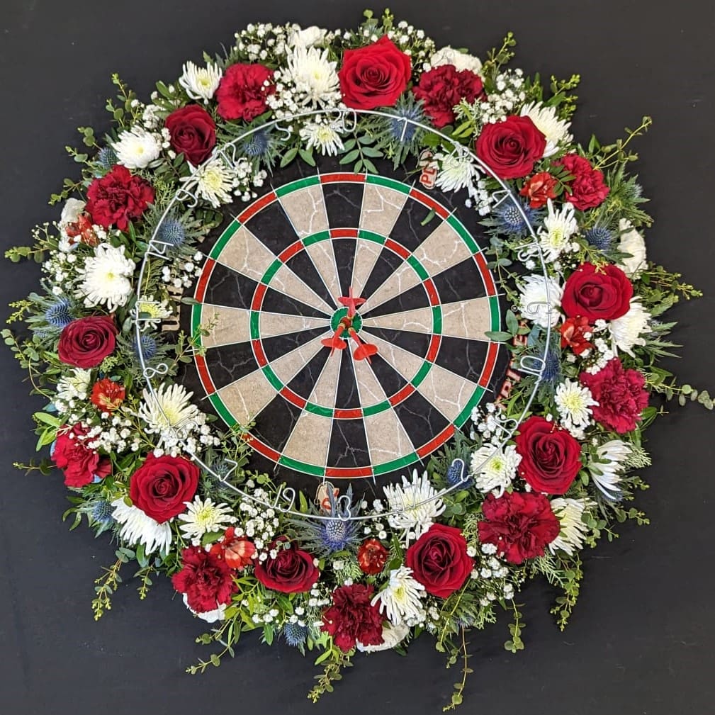 Funeral flower tribute with dartboard and red roses