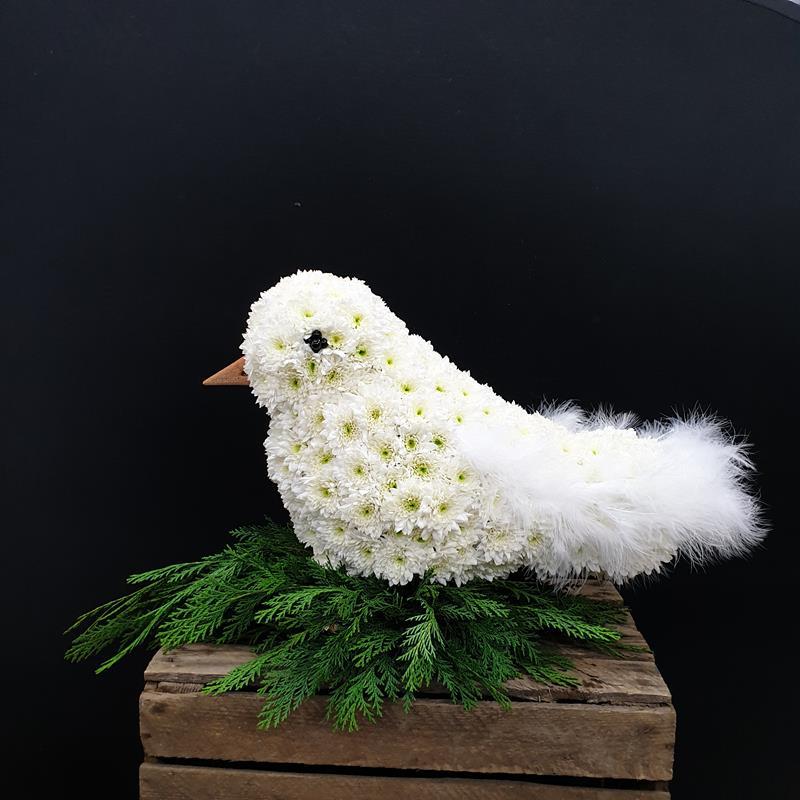 White dove-shaped funeral floral tribute with greenery