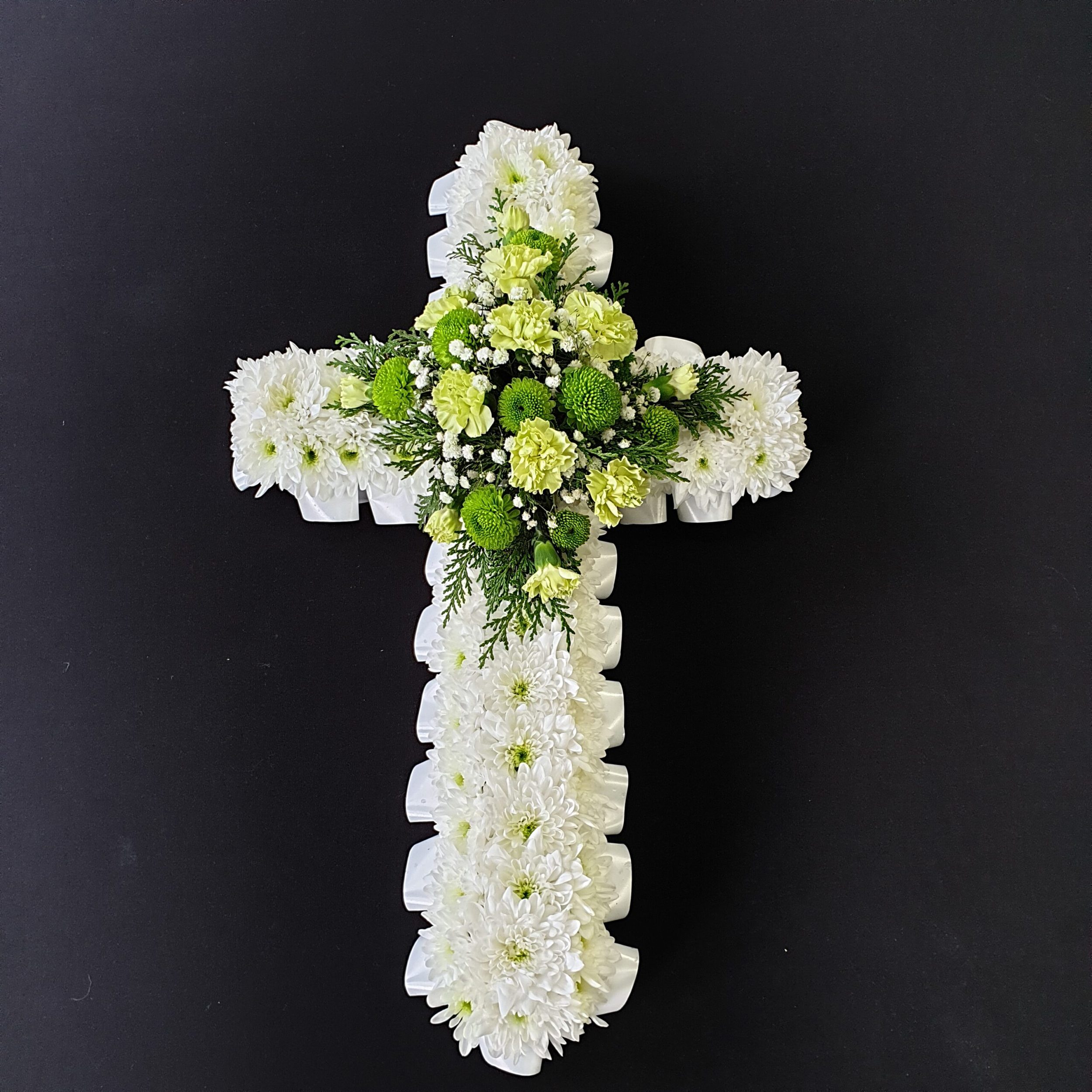 Green and white funeral cross with chrysanthemum base, lime carnations and green button chrysanthemums