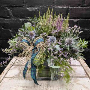 Scottish thistle and heather flower arrangement with lilac blooms, foliage and tartan ribbon in a glass cube vase – Anastasia Florists Aberdeen