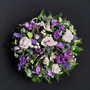Lilac and purple funeral posy with lilac roses, lisianthus, thistles and mixed flowers