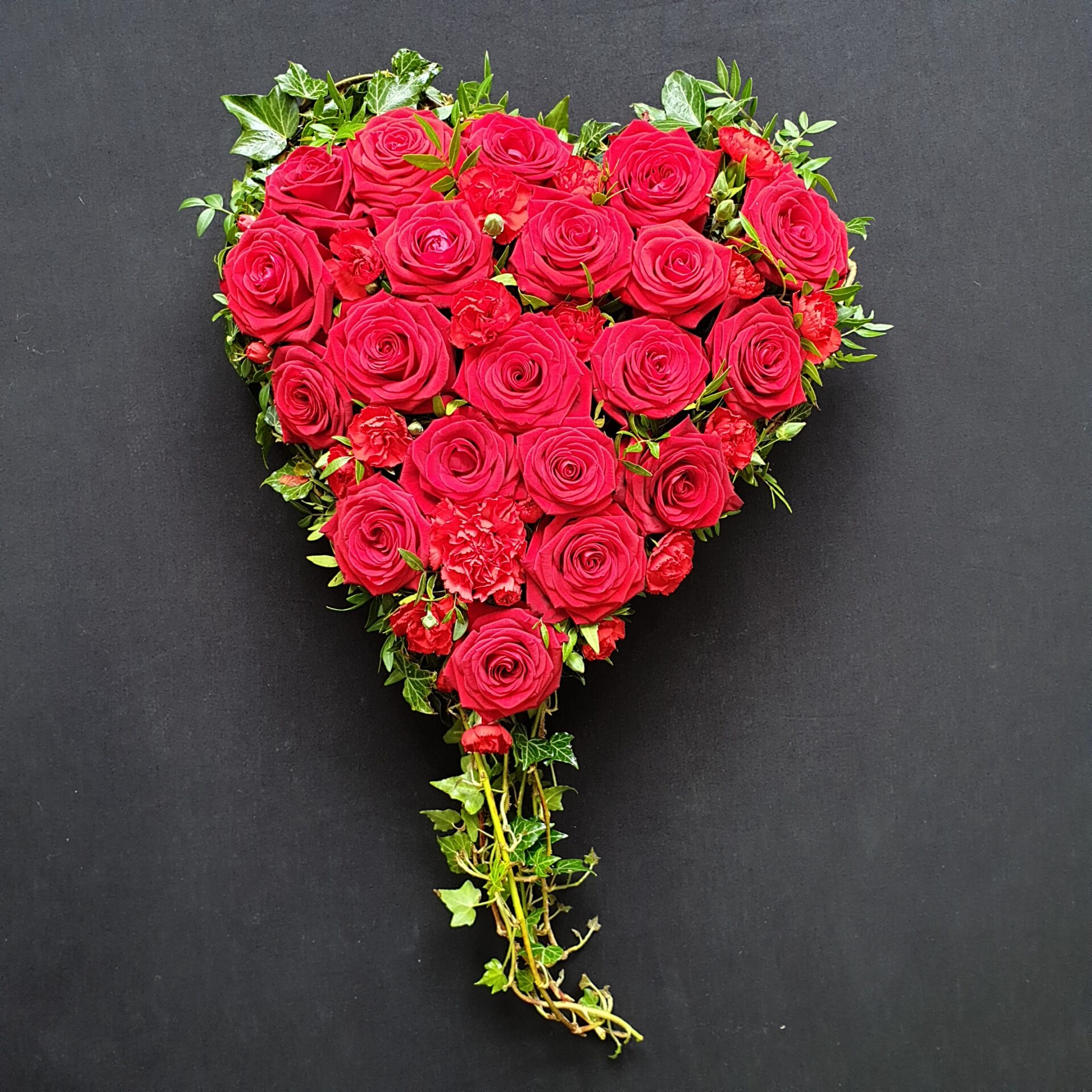 Red rose funeral heart tribute with greenery