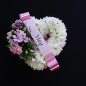 Miniature white chrysanthemum heart funeral wreath with pink flowers and a personalised pink “Meg” ribbon on a black background