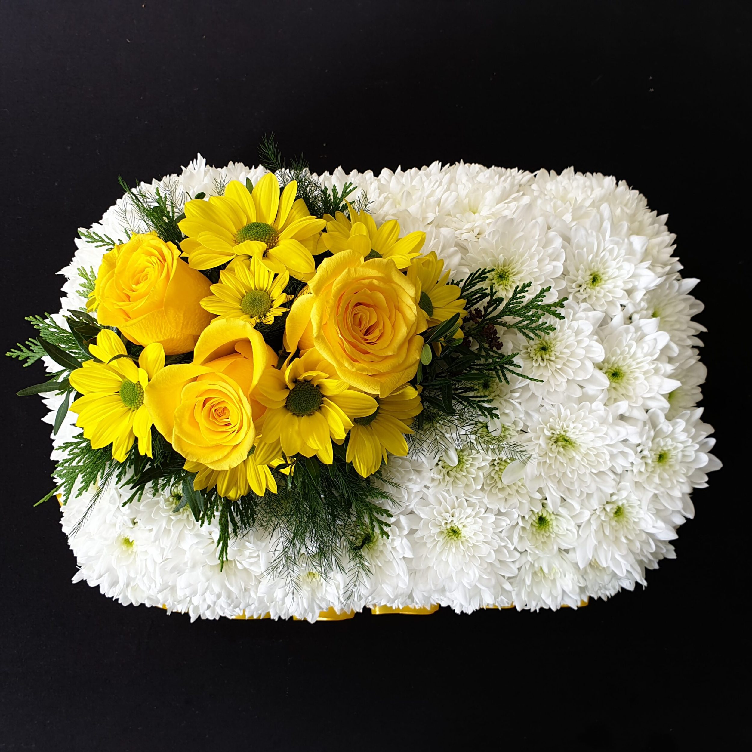 Miniature white chrysanthemum funeral pillow with yellow roses and daisy flowers on a black background