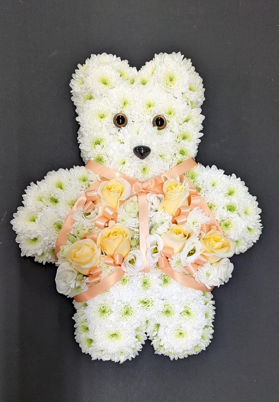 Floral teddy bear funeral tribute with white and yellow flowers