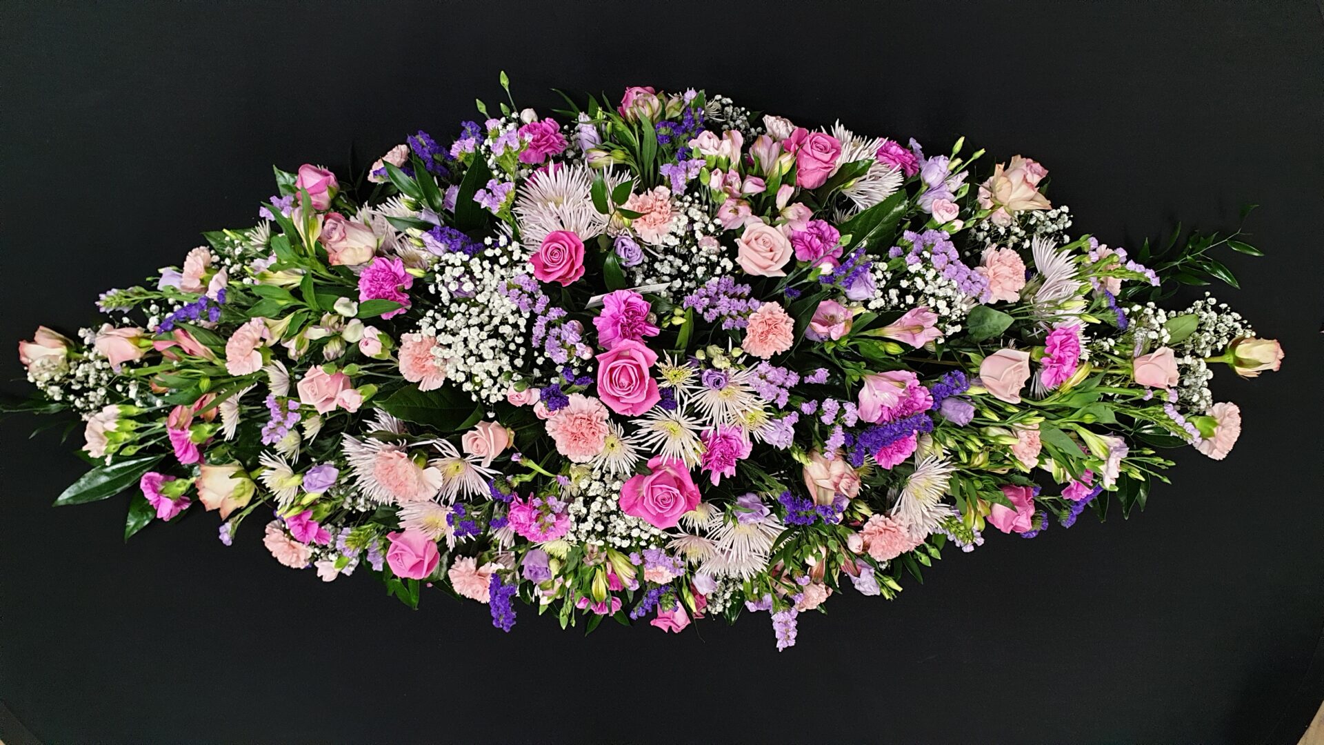 Pink and lilac coffin spray with roses, chrysanthemums, carnations and gypsophila