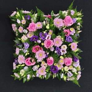 Pink and purple funeral cushion tribute with roses, gerberas and lisianthus