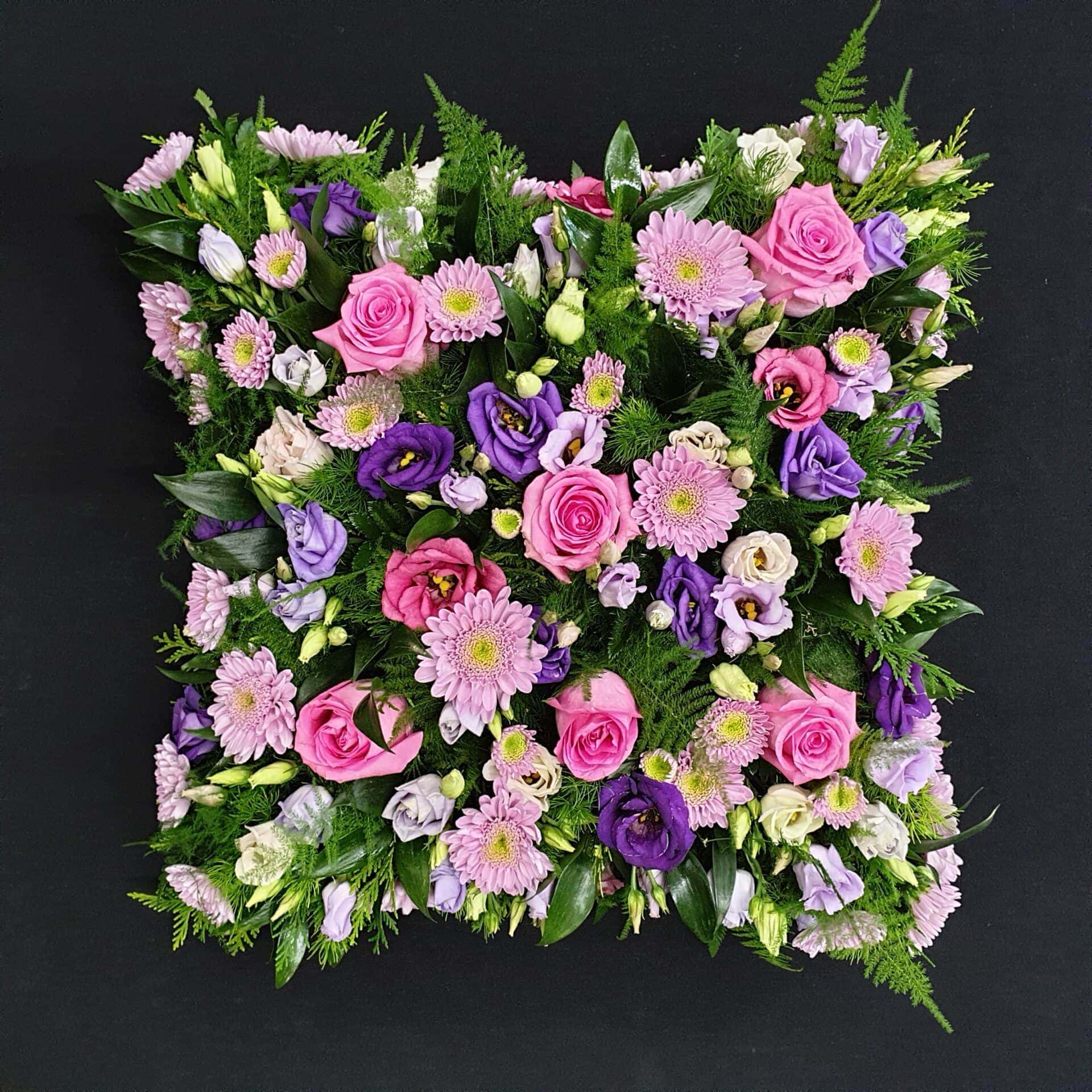 Pink and purple funeral cushion tribute with roses, gerberas and lisianthus