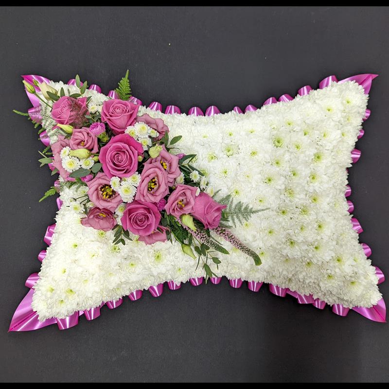 Pink rose funeral pillow tribute with white chrysanthemum base and pink ribbon edge