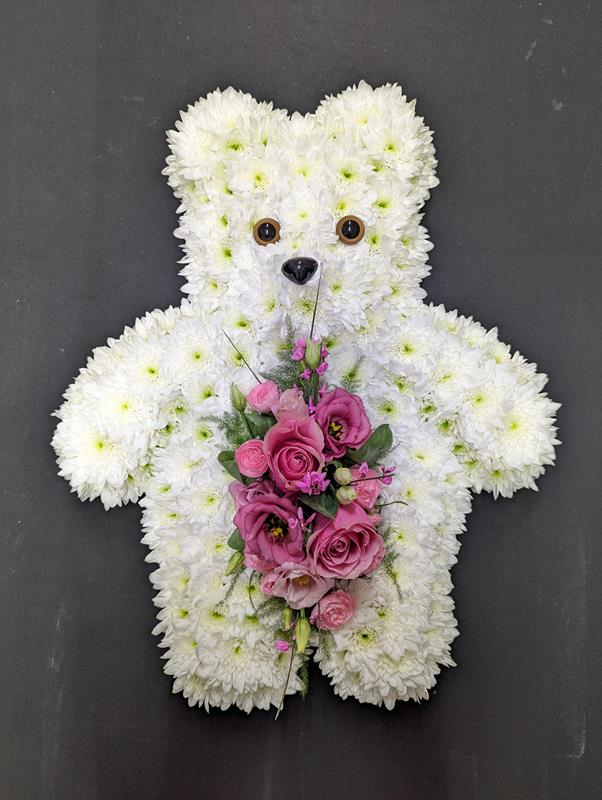 White teddy bear funeral tribute made from chrysanthemums holding a pink rose and lisianthus posy from Anastasia Florists Aberdeen.