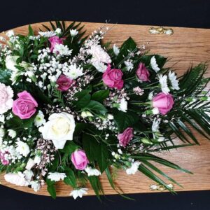 Funeral spray with pink and white roses on a coffin