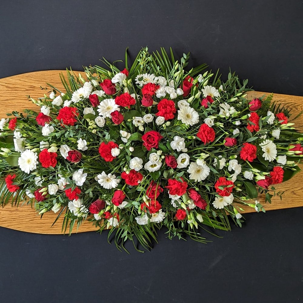 Red and white coffin spray with roses, carnations and gerberas on wooden coffin