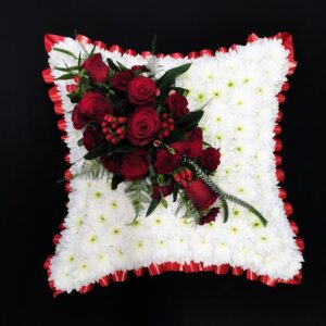 Red rose funeral cushion tribute with white chrysanthemum base and red ribbon edge