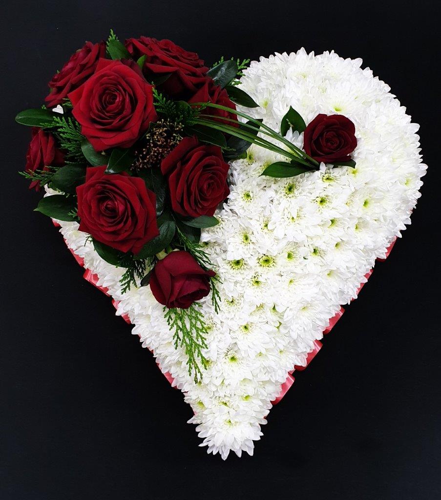 Heart-shaped funeral tribute with white flowers and red roses