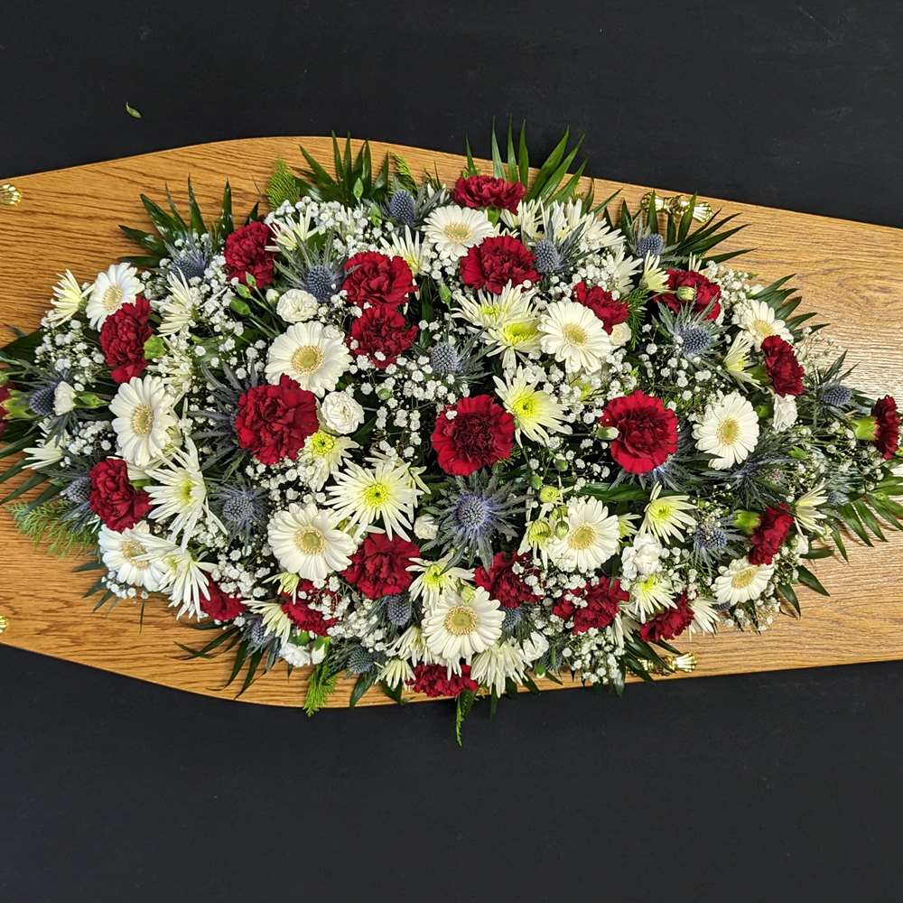 Red, white and blue coffin spray with carnations, gerberas, chrysanthemums and thistles on wooden coffin