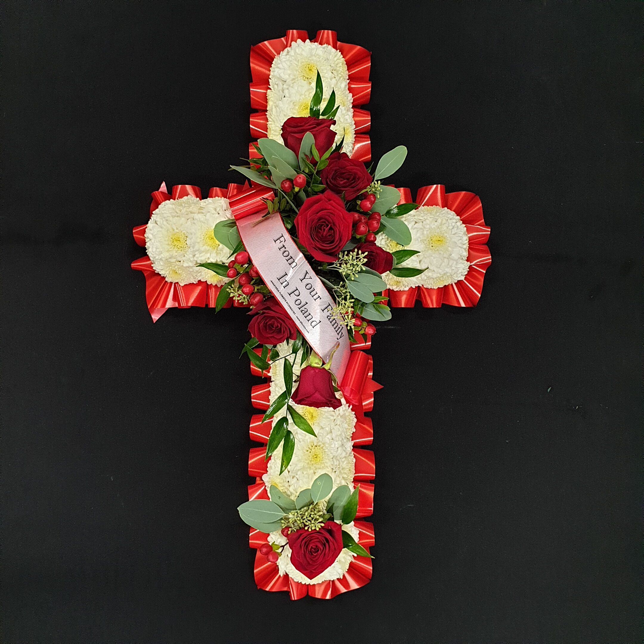 Red and white funeral cross with chrysanthemum base, red roses and ribbon tribute