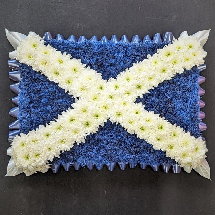 Scottish flag funeral tribute with blue base and white chrysanthemum Saltire cross
