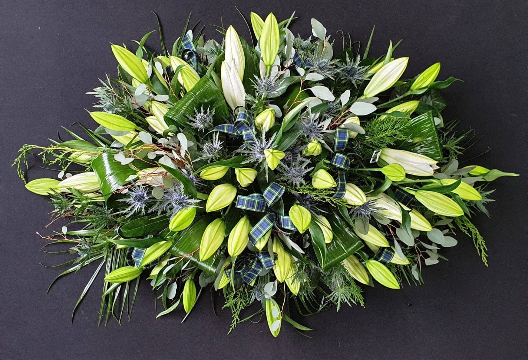 Scottish white lily coffin spray with blue thistles, eucalyptus and tartan ribbon