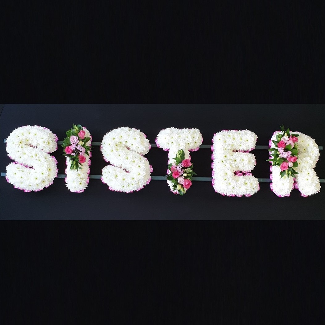 SISTER funeral letter tribute with white chrysanthemums, pink ribbon edging and pink rose sprays